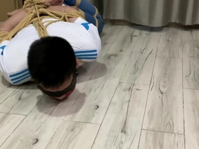 Young Asian man tied up and struggling in white socks and jeans